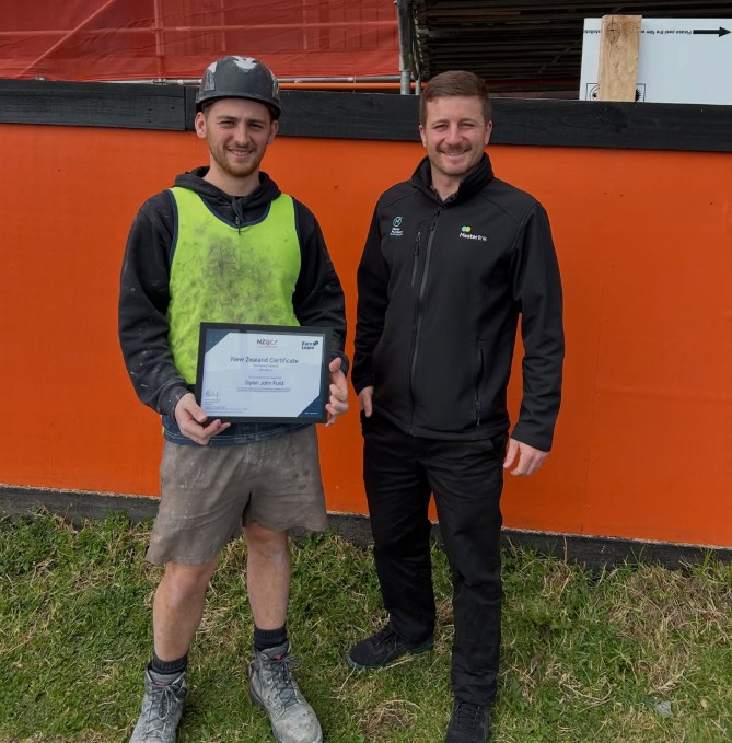 Two men, one holding a certificate, smiling.